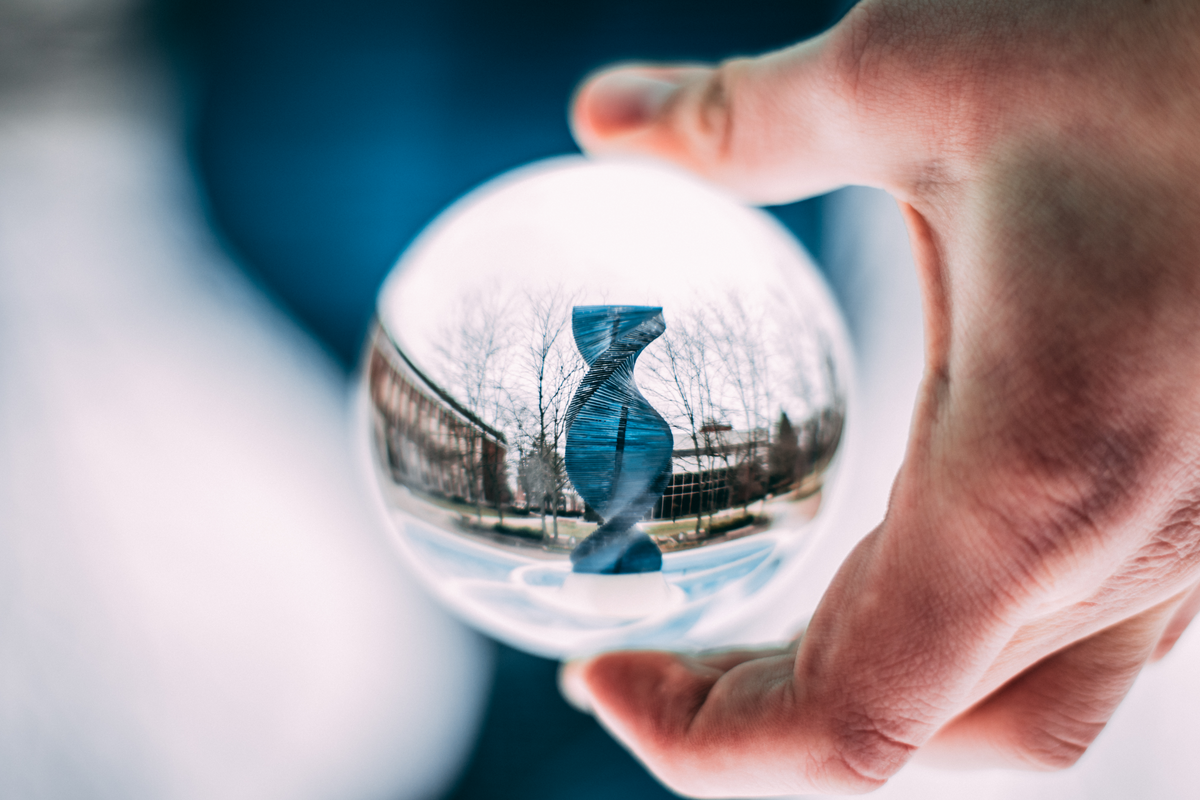 Person Holding Sphere Reflecting Dna-shaped Statue